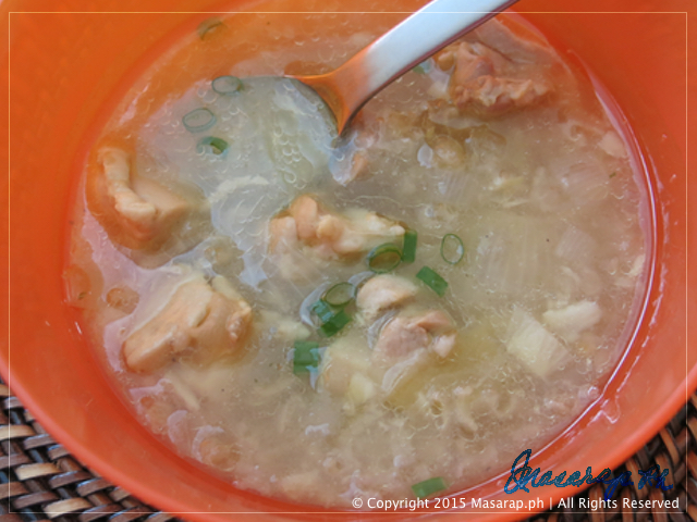 arroz caldo manok in an orange bowl with a spoon